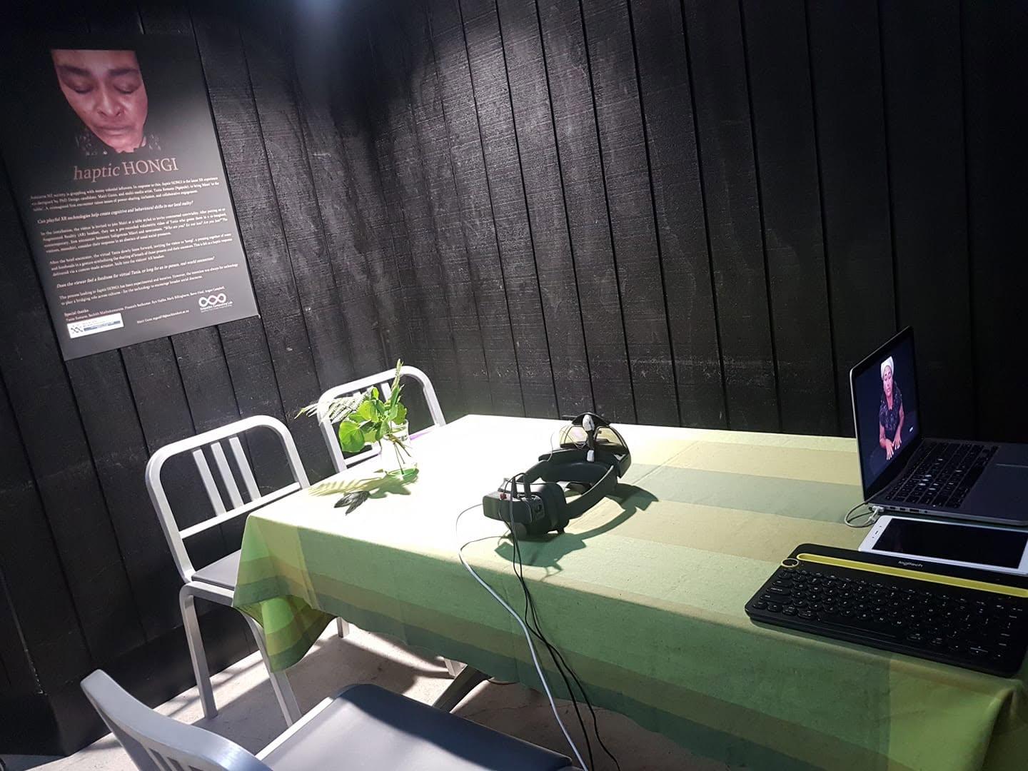 The demo table in Sydney: tablecloth, flowers, a headset, and a woman waiting on a laptop screen The demo table in Sydney, dressed as a dining room